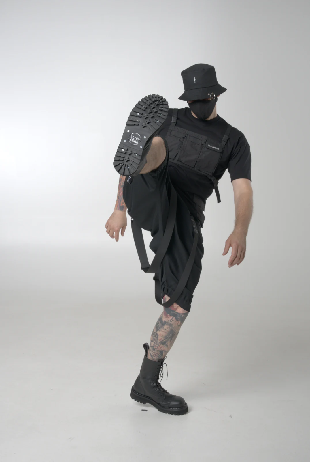 An LF black outfit with a pocket-panel T-shirt and cropped loose trousers, photographed in a raised-leg pose