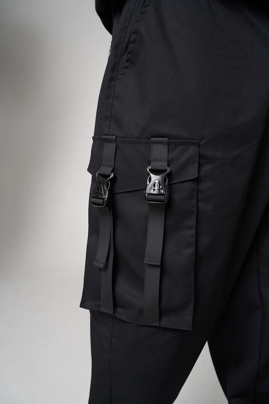 Close-up of an LF black cargo pocket with a flap, two webbing straps and two buckles
