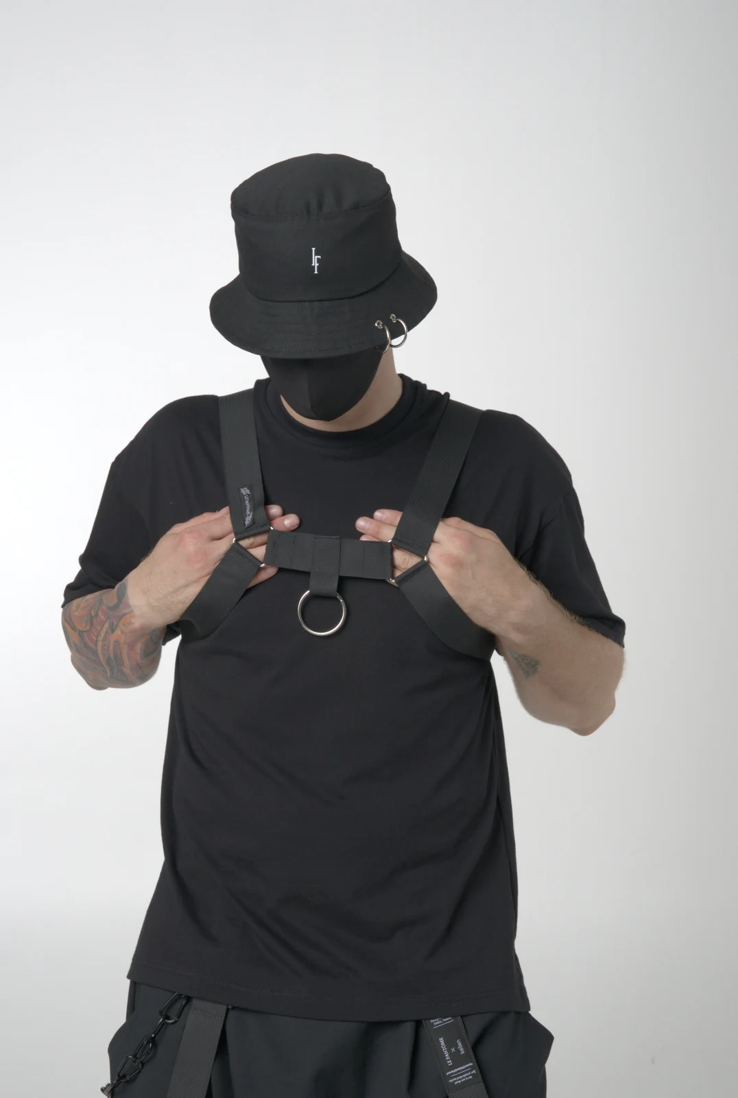 A black LF fashion harness with broad straps and a central ring, layered over a plain black T-shirt