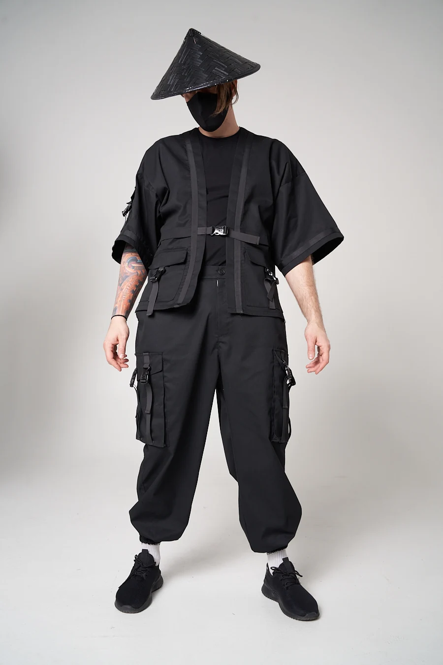 LF black short-sleeved outer layer with a buckle closure and front pockets, worn over wide cargo trousers in a styled campaign look