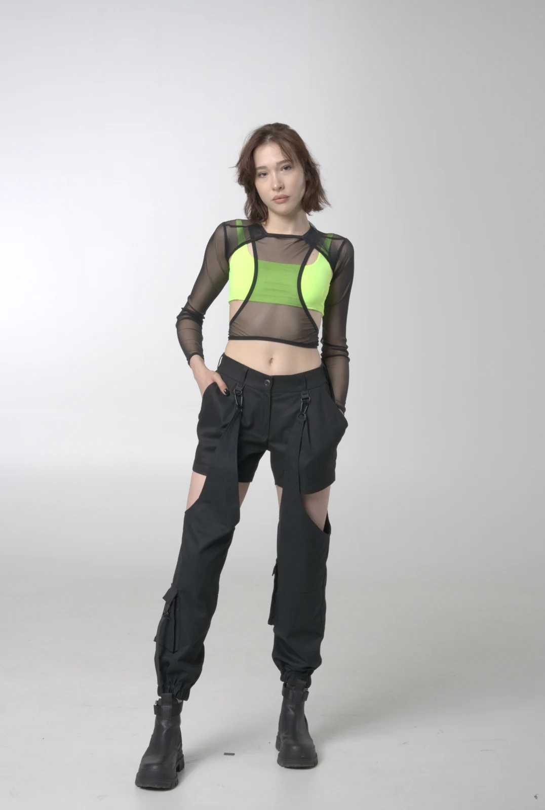 An LF look combining black cut-out cargo trousers, a sheer black top and a bright green underlayer